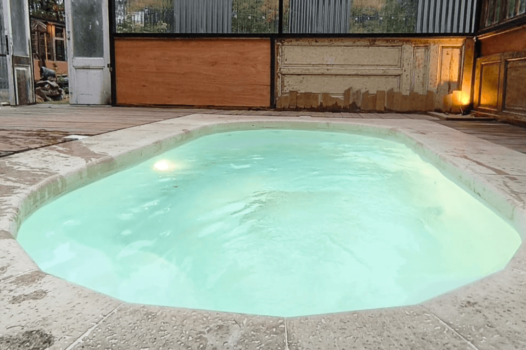 Piscina de fibra de vidrio llena, con vereda perimetral e iluminación encendida